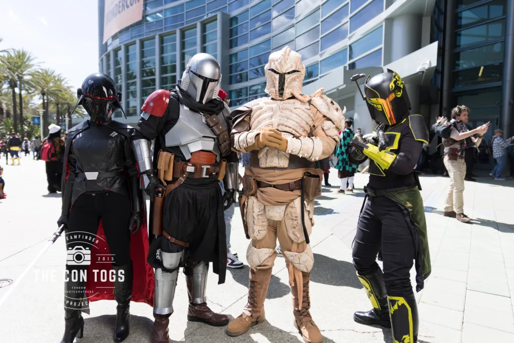 Four figures in Mandalorian armor and a stylized bounty hunter costume pose for a photo at WonderCon.