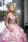 A performer portrays Glinda, the Good Witch of the North, in a voluminous pink gown, holding a sparkling wand.
